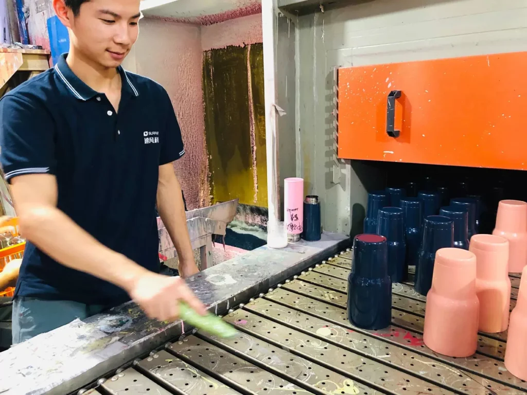 Worker beside a custom water bottle powder-coating booth