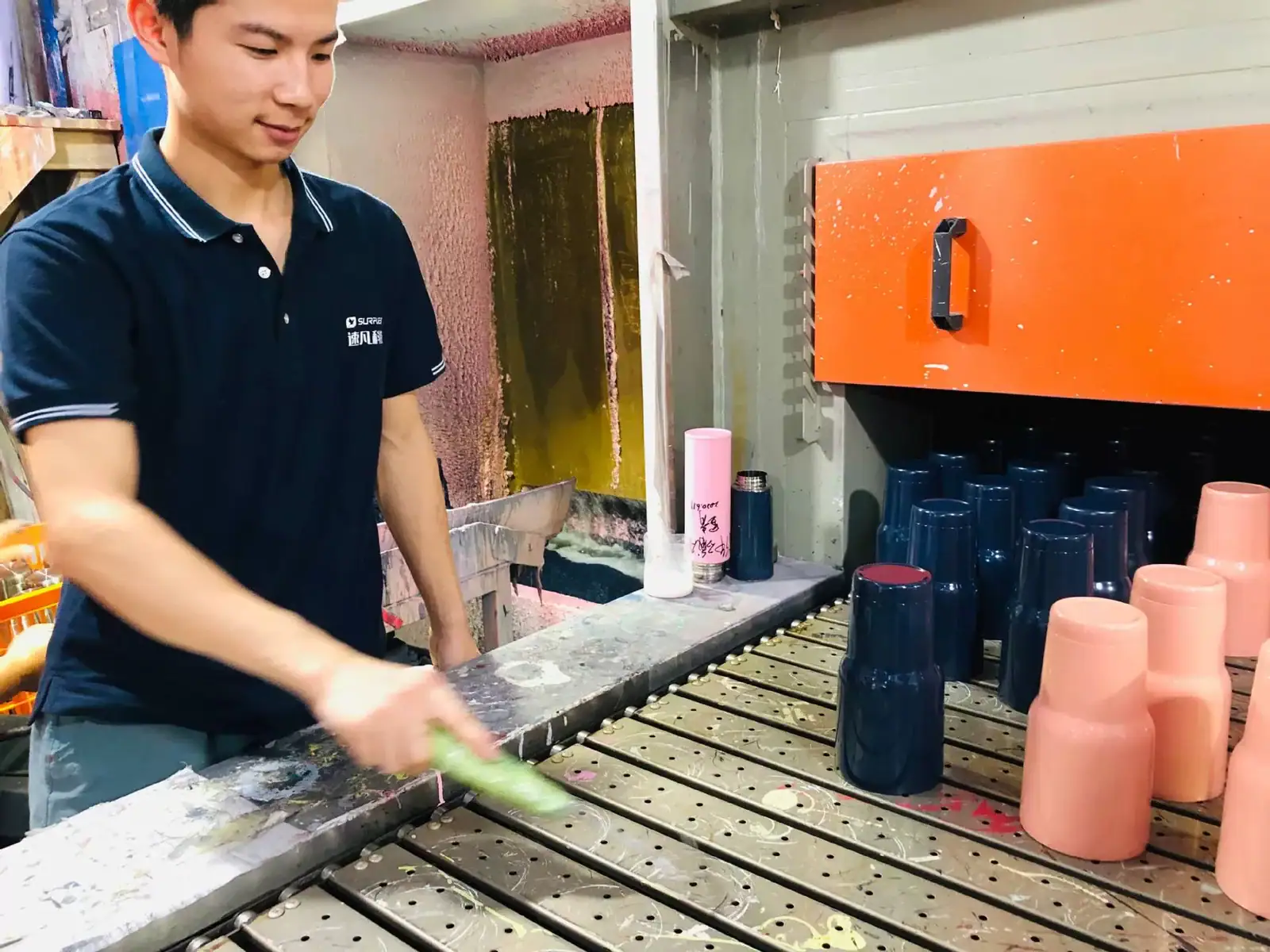 Worker beside a custom water bottle powder-coating booth