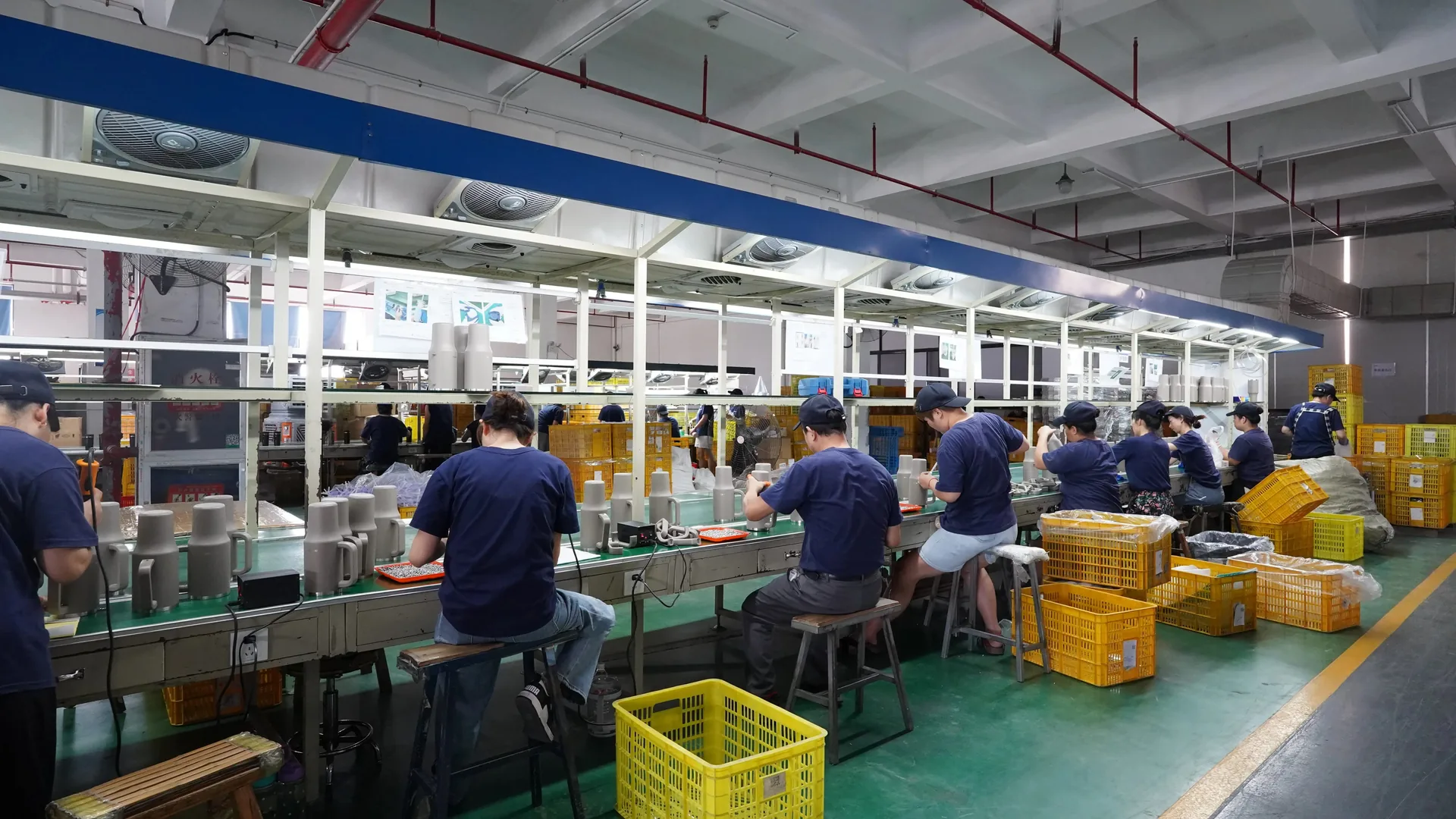 Workers checking drinkware components along a factory production line