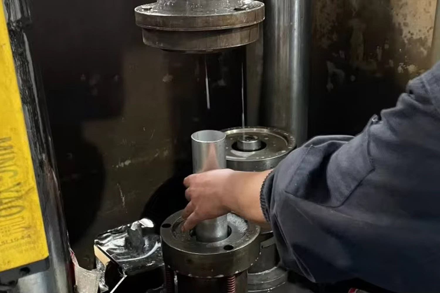 Operator positioning a stainless steel tumbler body during bottom-forming production