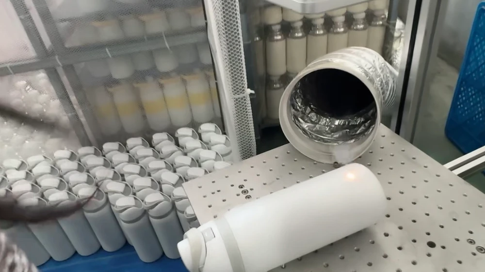 White bottle positioned on a perforated worktable beneath an extraction hose