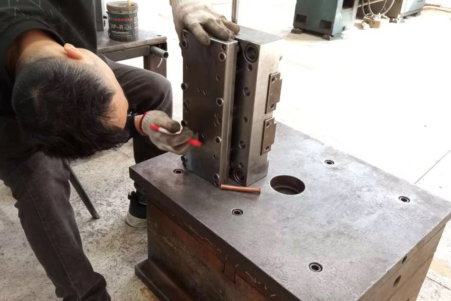 Worker checking a metal forming tool during stainless steel cup production