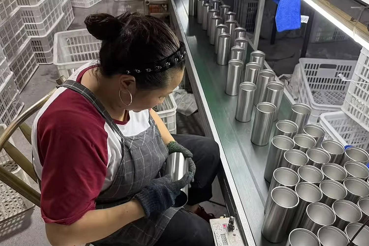 Worker inspecting unfinished stainless steel cup bodies before the next production stage